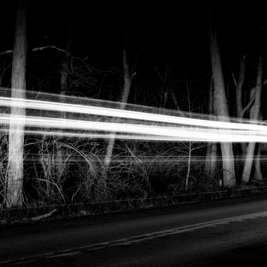 Black and white extended exposure photograph of car light trail in woods in Huntingdon, Pennsylvania